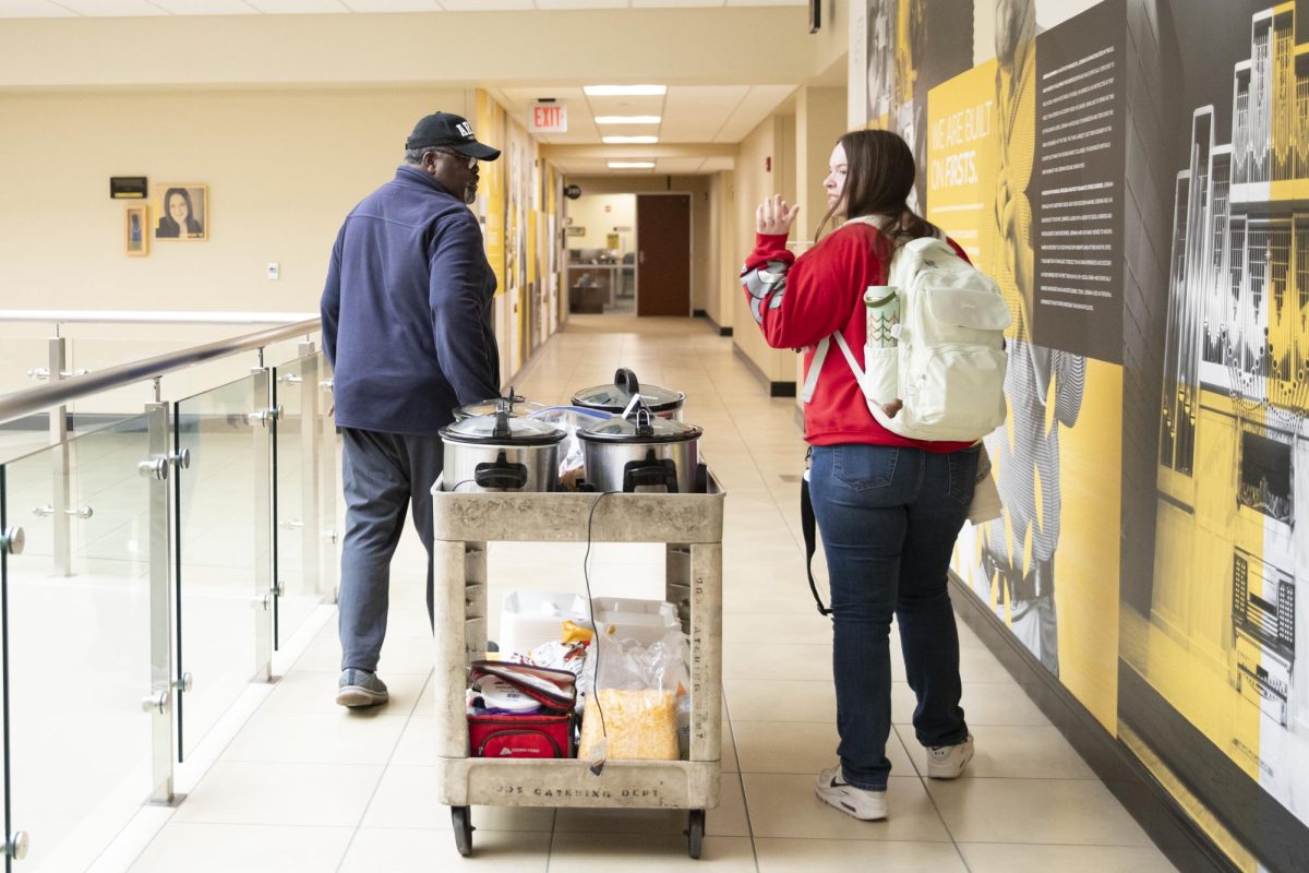 Larry Burks Sr. and Sierra Riley transport the chili for Veteran Students Organizations first event of the year from the second to first floor of the Rhatigan Student Center on Feb. 13. Students were able to get a bowl of chili for $3, with the proceeds going to the organization.
