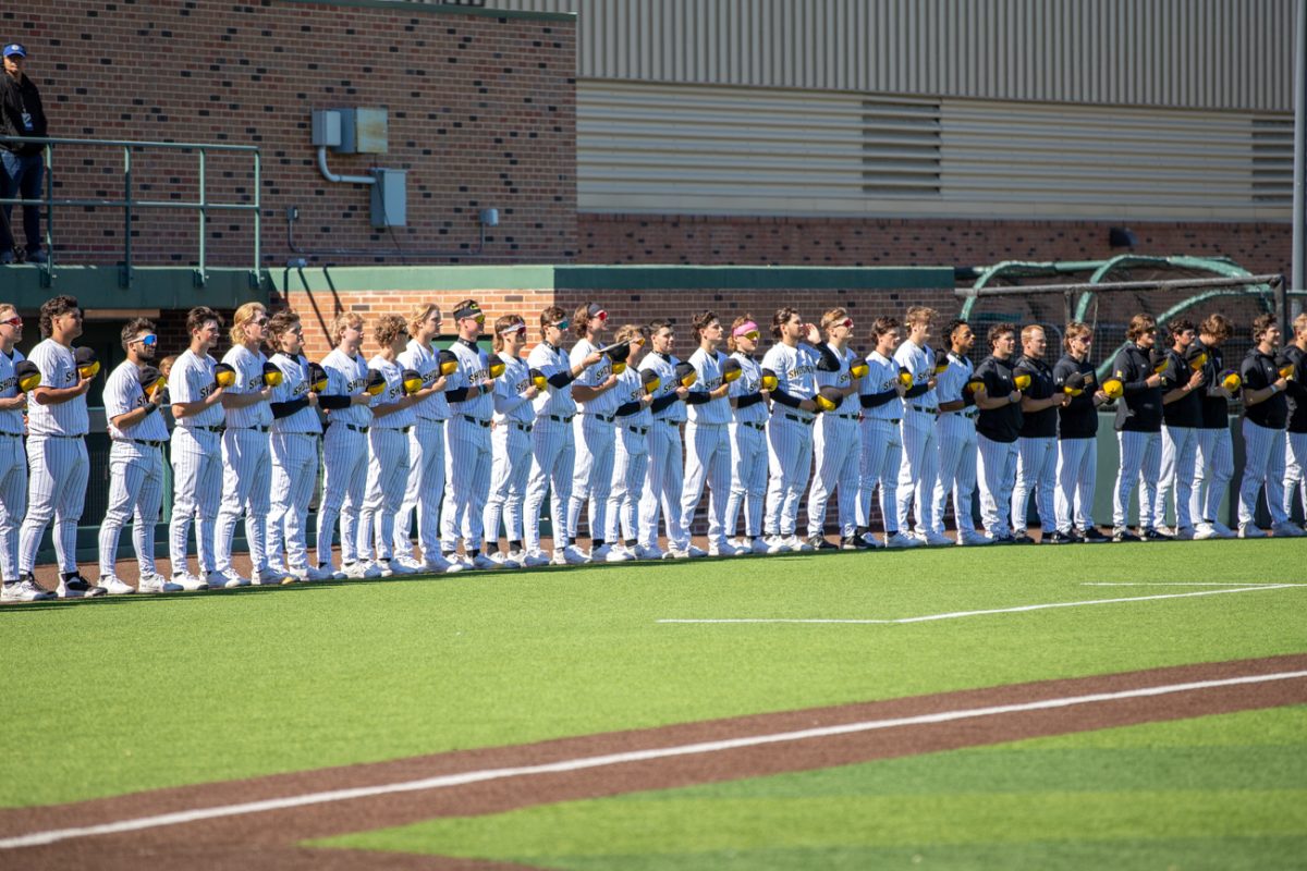 The Wichita State mens baseball team stand with their hats in their hands for the National anthem before their game against Dirtbags on March 9.
