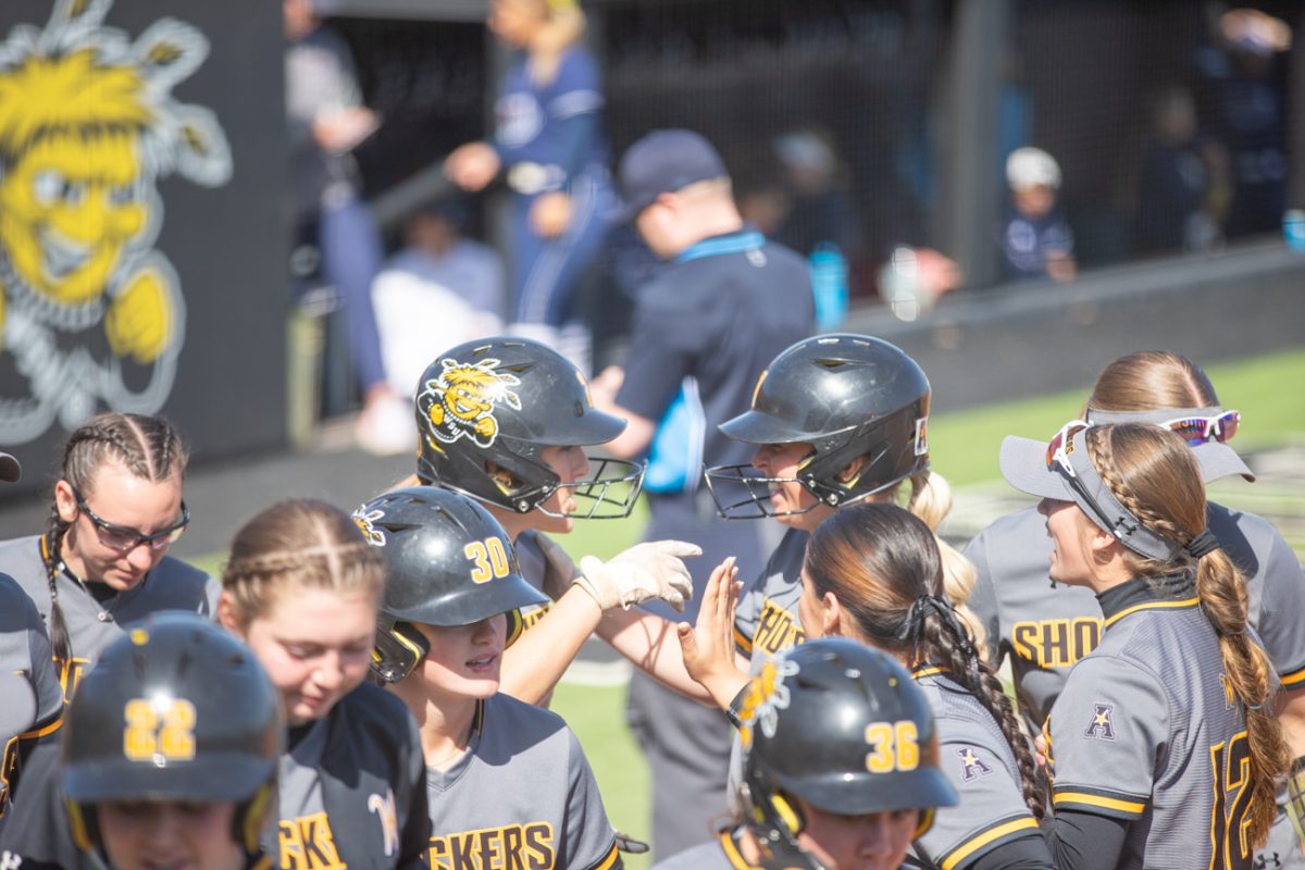 The Wichita State softball team cheers and taps on the hat of Taylor Sedlacek after she got a run against Florida Atlantic on March 10.