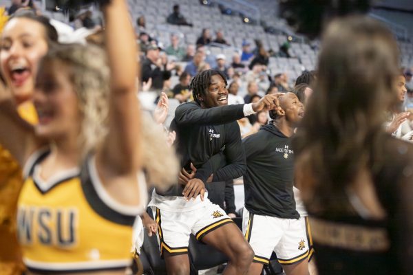 Redshirt sophomore forward Isaac Abidde cheers with the mens basketball team and university Spirit Squad after a successful play by the Shockers. WSU defeated Rice University by seven points, 88-81.