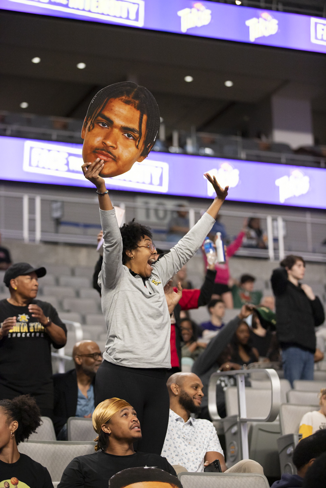 Holding a cutout of Kenny Pohtos head, a Wichita State fan cheers as the Spirit Squad throws t-shirts into the Dickies Arena crowd.