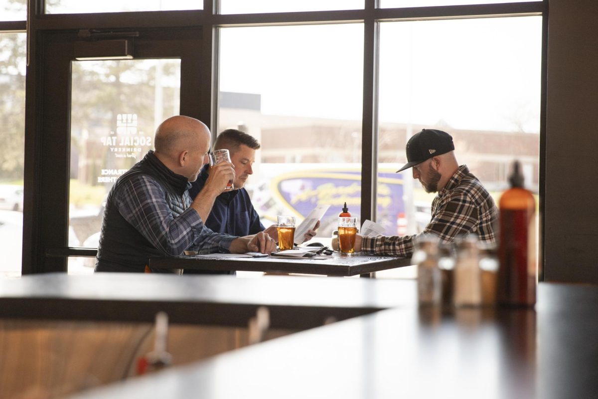 Luke Luttrell, Justin Neel and David Hopkins sit and discuss finances for their restaurant Social Tap on a Monday afternoon. The alumni all attended Wichita State.