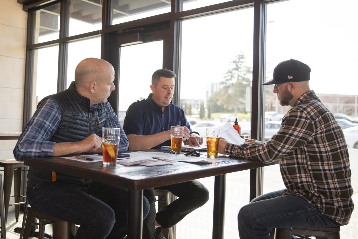 Luke Luttrell, Justin Neel and David Hopkins sit and discuss finances for their restaurant Social Tap on a Monday afternoon. The alumni all attended Wichita State.