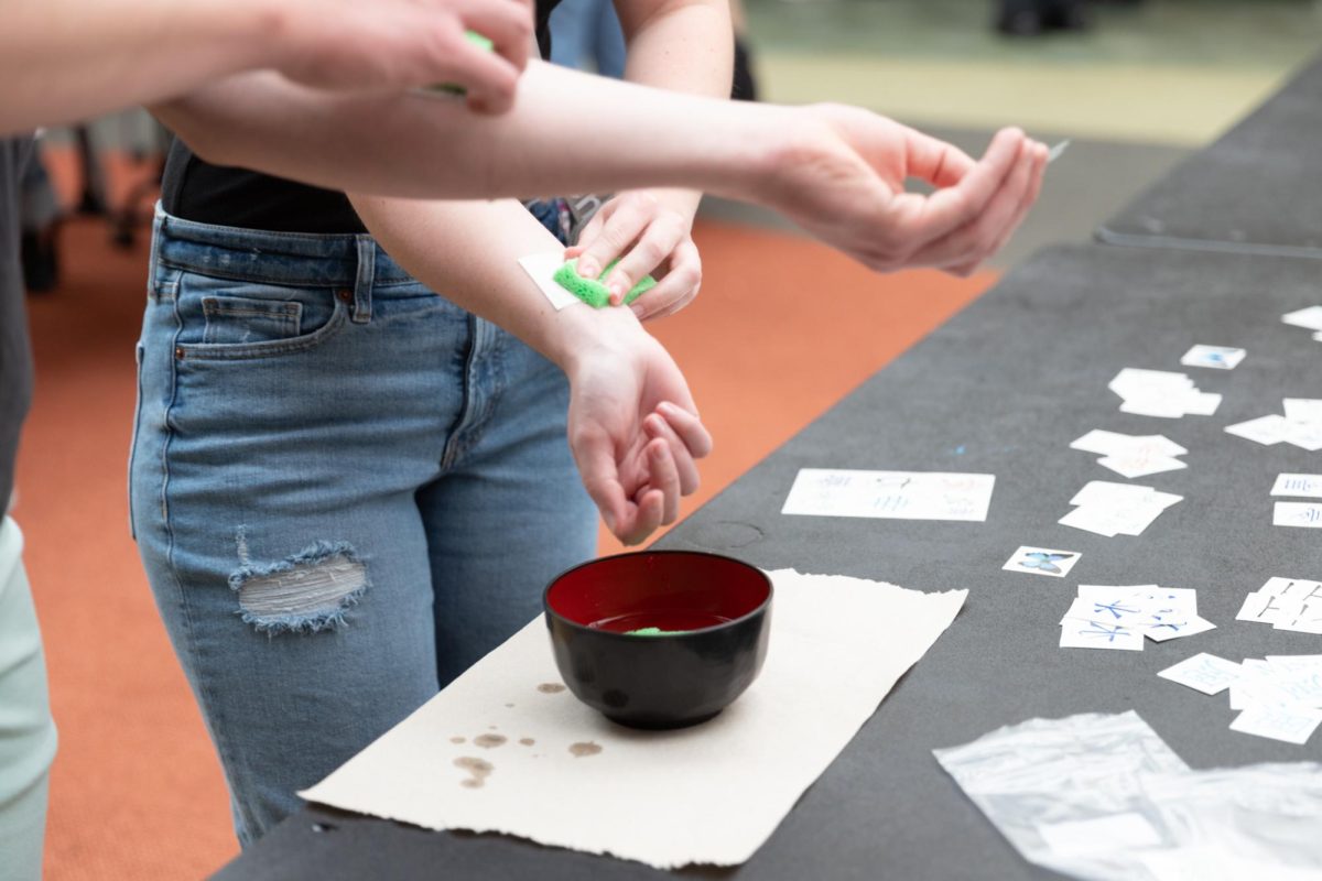 Students apply Kanji temporary tattoos at the Japan Festival held by Asian Student Conference Dance and the Japanese Cultural Association. 