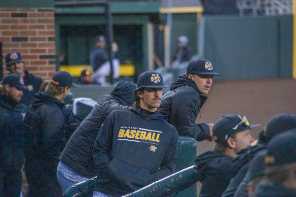 WSU baseball players watch the game from home dugout. On March 25, Wichita State played against Oklahoma State at Eck Stadium.