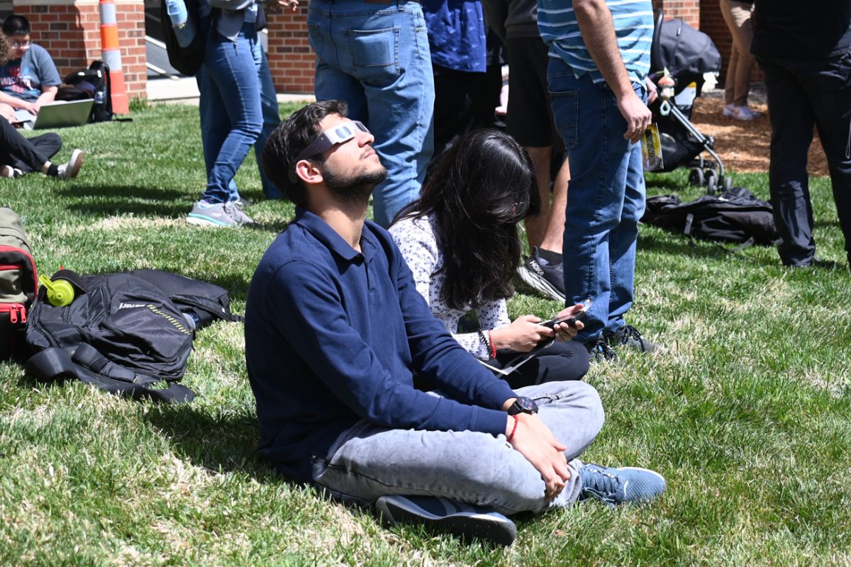 Students sit outside on the south side of Jabara Hall using glasses to view the solar eclipse on April 8th.