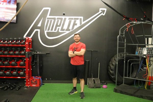 Andy Sykes poses in front of the logo for his Amplify My Training company on April 26.