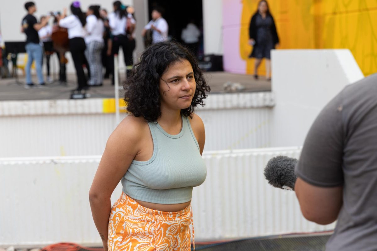 Colombian street artist and muralist Nathalia Gallego Sánchez, known in the art world as GLeo, speaks to a media source at the unveiling of her Adelante Juntos- Forward Together Duerksen Amphitheater mural on May 3.