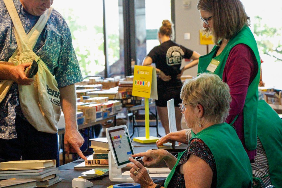 Cathy McElroy and Connie Kendall, volunteers with the museum, work together to check guests out, taking cards, Apple Pay and cash. The volunteers come in before the event to set up the booths and  take it all down once it ends.