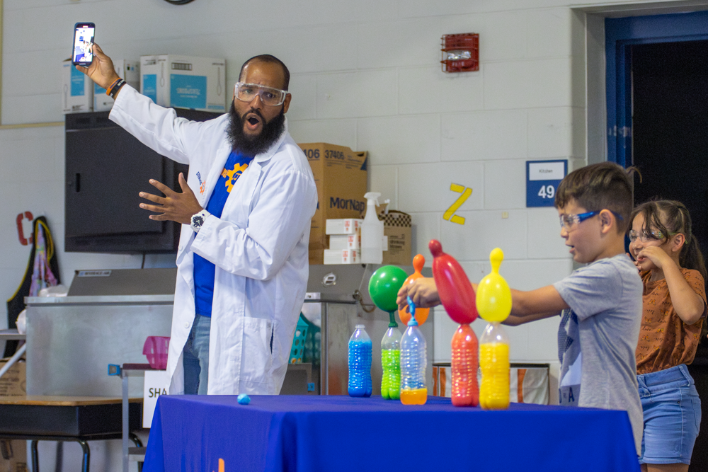 Roy Moye III records a video and looks on in surprise as students of Linwood Elementary participate in a baking soda and vineager experiment. Moye used the experiment to teach kids about the inquisitive nature of science and STEM careers.