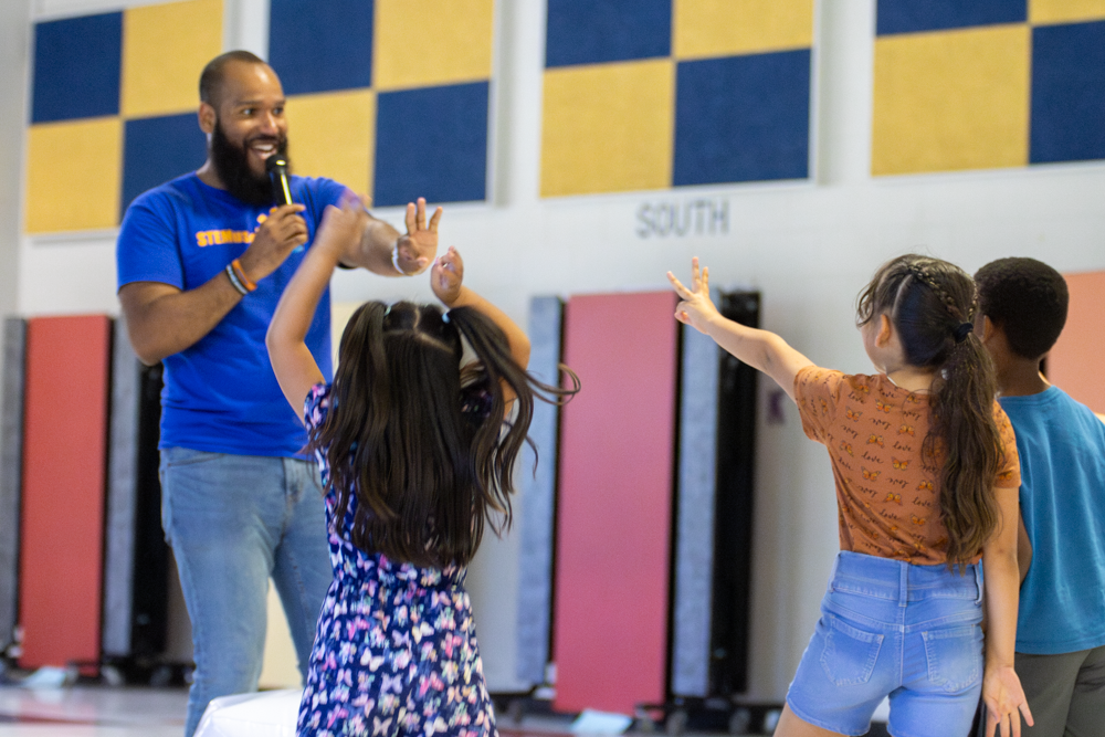 Roy Moye III leads students of Linwood Elementary through a math lesson in which he asked kids to add, subtract and multiply numbers on an inflatable die. Each student got to throw the die and then calculate the sums of various math problems.