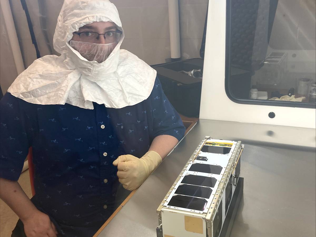 A graduate student poses for a photo with the finished CubeSat. Photo courtesy of WSU News.