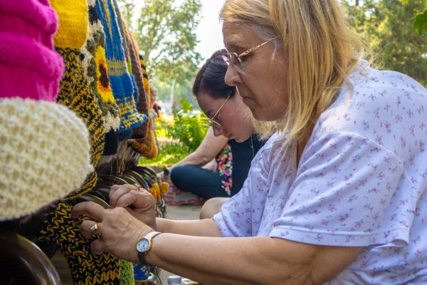 Shocker alumna and Sip and Stitch member Pam Cornwell and Ulrich Museum of Art gallery assistant Maddie Bowron work on the yarn bombing of Millie the Millipede, a sculpture by Wilner Auditorium created by artist Tom Otterness. Several current and former Ulrich employees, as well as Sip and Stitch members, gathered on Aug. 27 to yarn bomb the sculpture.