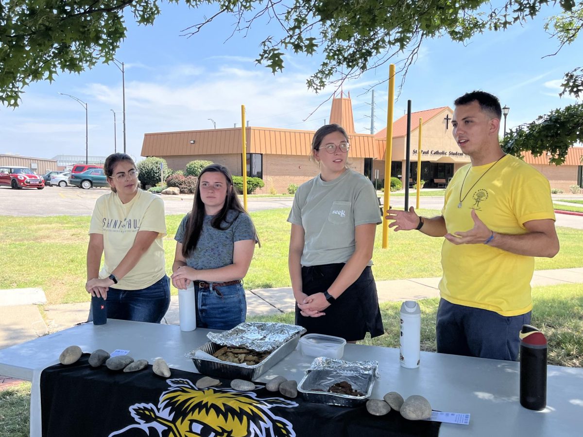 Adriana Lazalde, Kayla Fleming, Alexis Cherveny and Jose Gonzalez table outside the St. Paul Catholic Student Center, handing out cookies and providing information about the fellowship program.