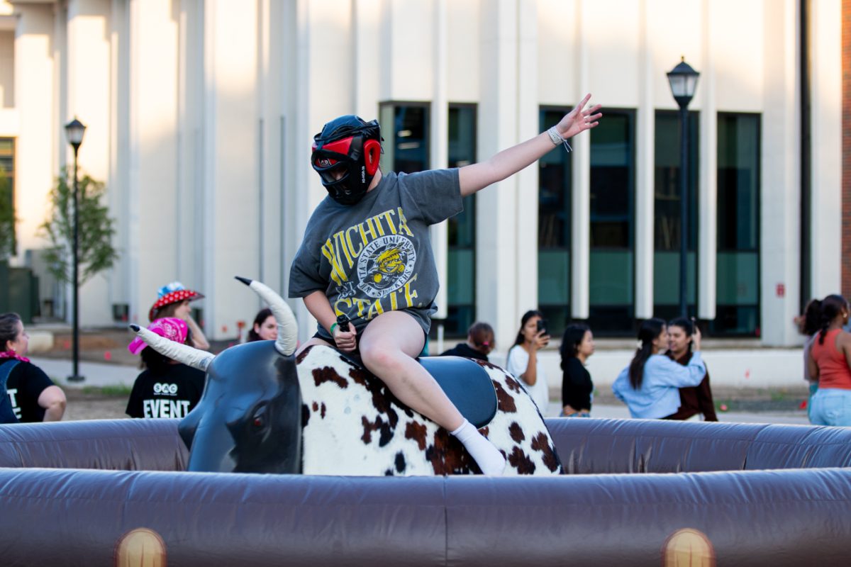 Freshman Lexi Sanders hold on to the mechanical bull as it spins and tries to buck her off. The event was free to all WSU Students, and held outside the RSC on Aug. 22.