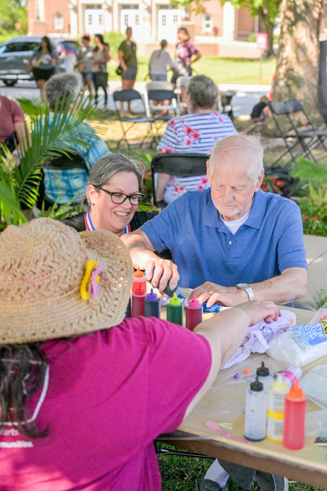 Jennifer Bolyard, the Comfort Care Homes director of engagement, and Meghan Miller, a local artist, assist Richard Hill, 84, in creating his tie-dye bandana.