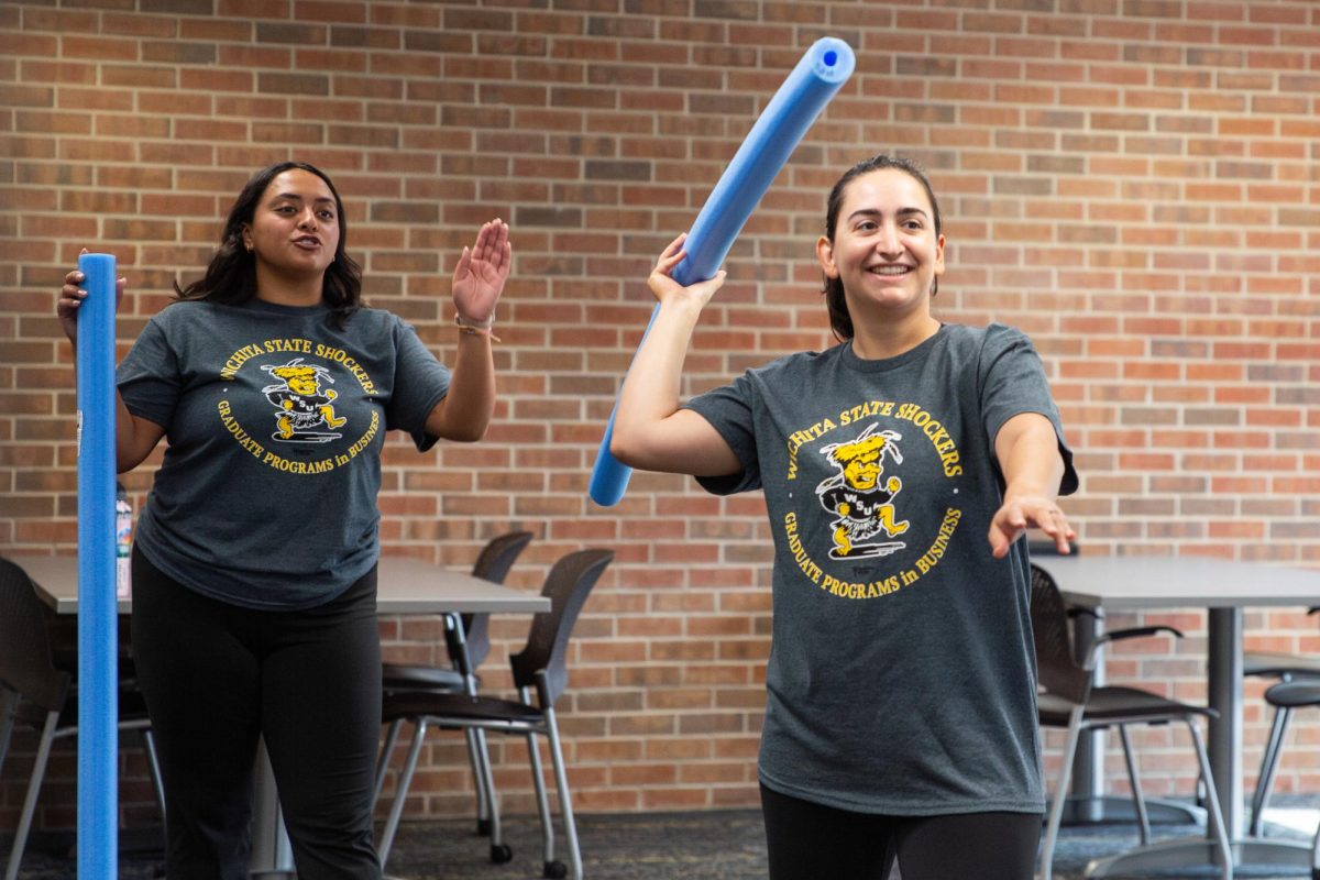 Natanya Ordoñez advises Sofía Polanco Botteselle on how to throw her pool noodle into hula hoop goals. The "javelin" activity was one of the first hosted at Ablah Library for the inaugural Faculty/Staff Olympics on Aug. 1.