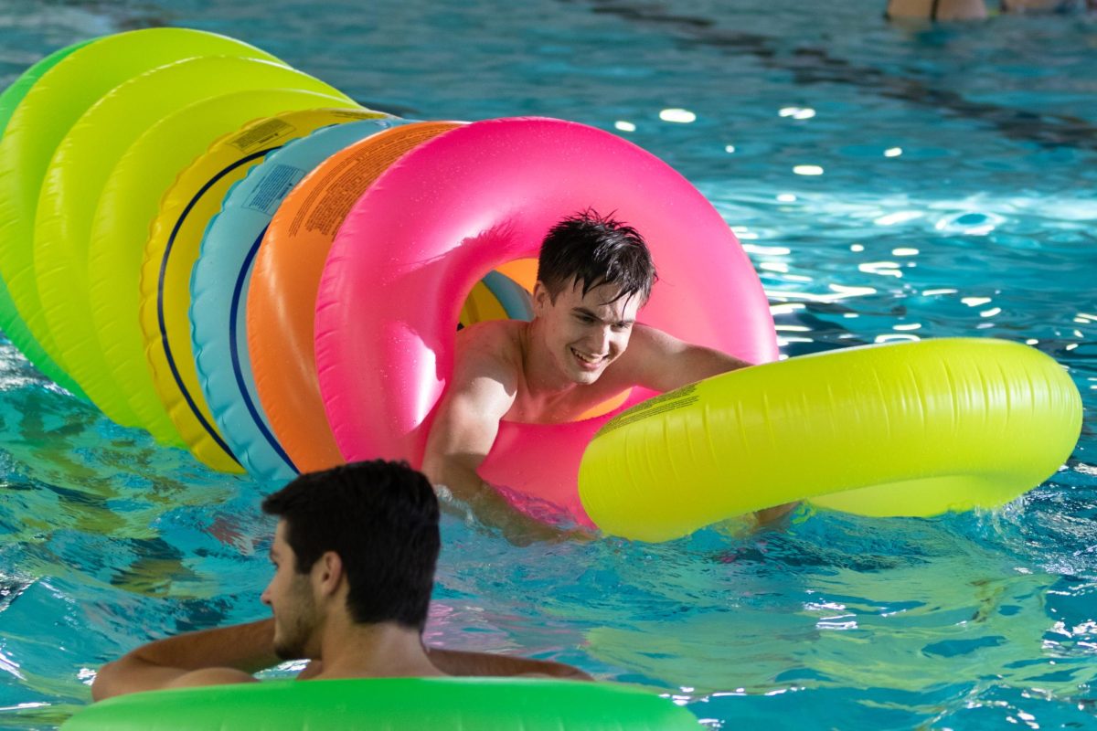 Sophomore aerospace engineering major Joseph Snodgress becomes a "human worm" with different colored floaties at the back to school pool party on Aug. 15.