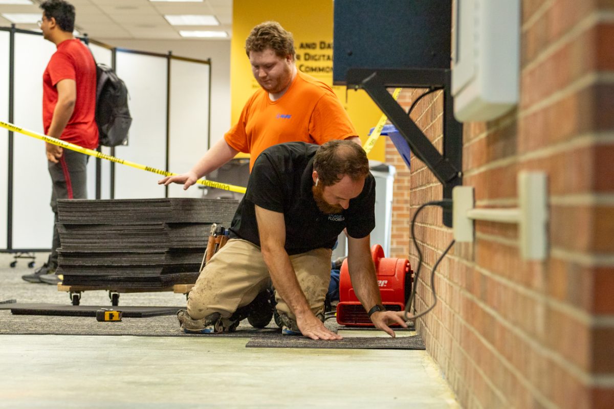 Constuction workers work on removing and replacing the carpets on the first floor of Ablah Library. The library is going through renovations including new flooring and walls in some areas.