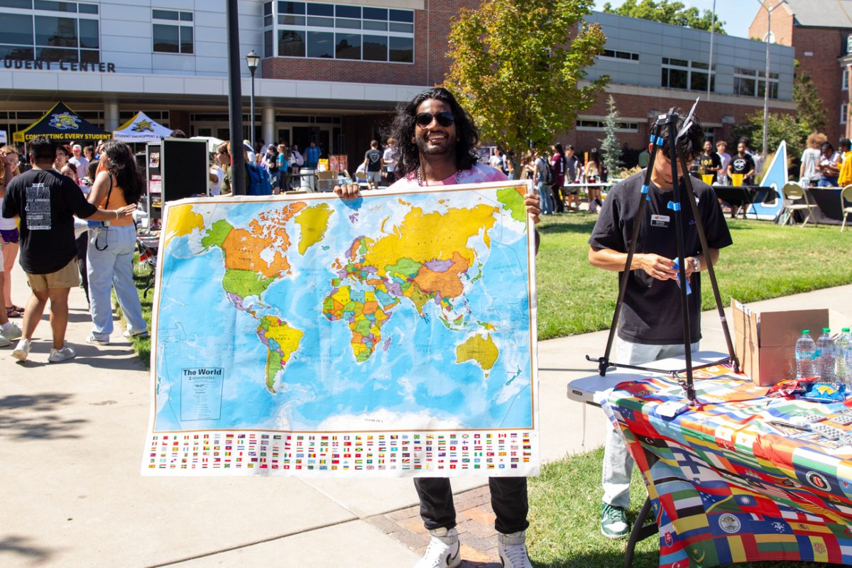 student vishnu avva holds up a map at the international student table. avva is a big advocate for equality and culture appreciation.