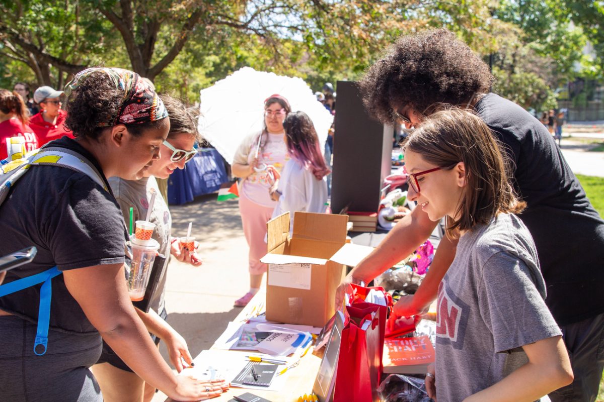 students at a booth converse with fellow students about the club they represent.