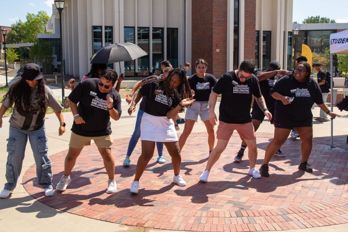 staff from the student engagement and belonging office dance along to the cha cha slide. a handful of students join their fun.