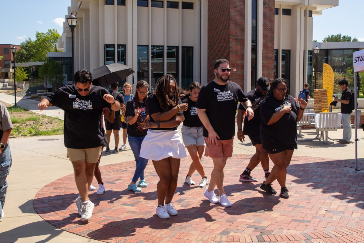 staff from the student engagement and belonging office dance along to the cha cha slide. a handful of students join their fun.