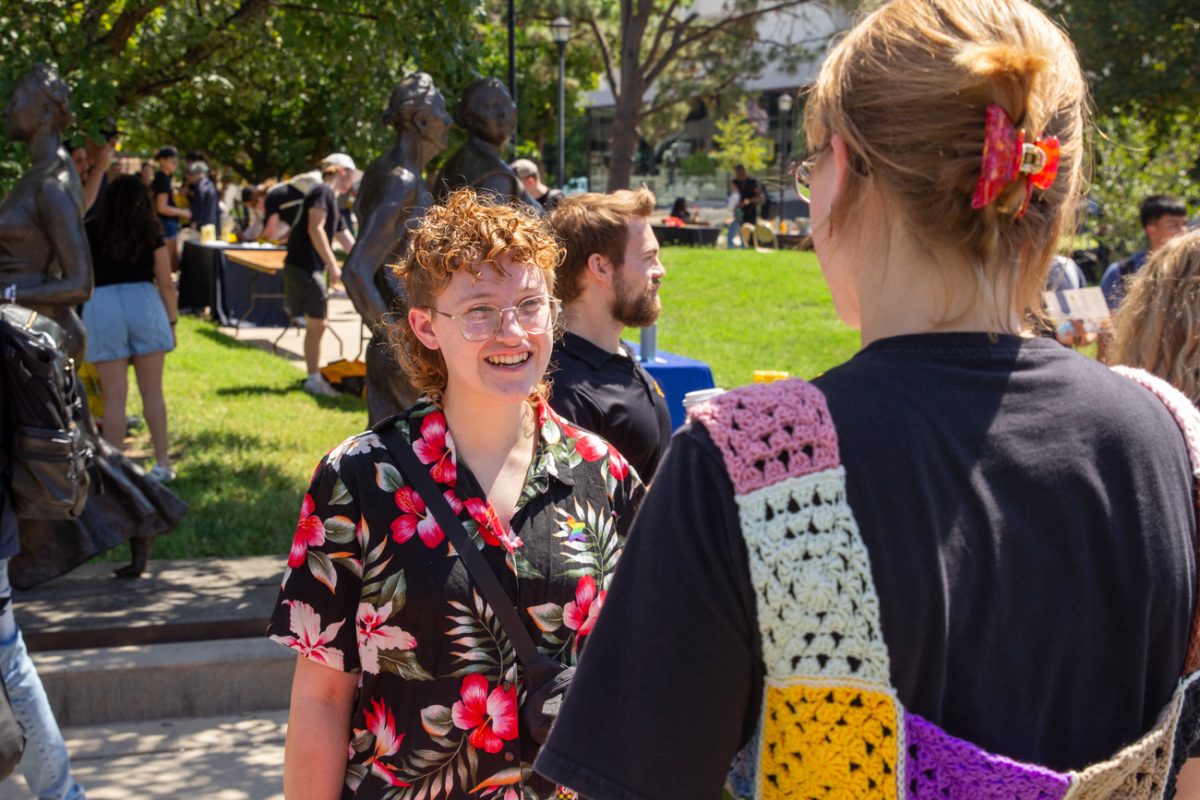 student elaine swan talks to a lgtbq+ programs representative about their mission. the representative tells swan about all of the success the program has had.