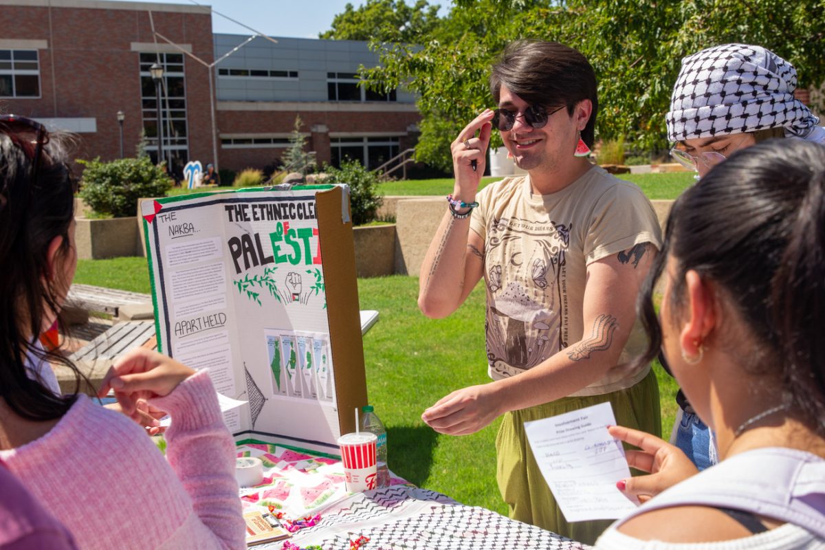 students supporting the palestine movement tell visitors about their efforts and sign scavenger hunt cards. the students are very engaged and interested in participating.