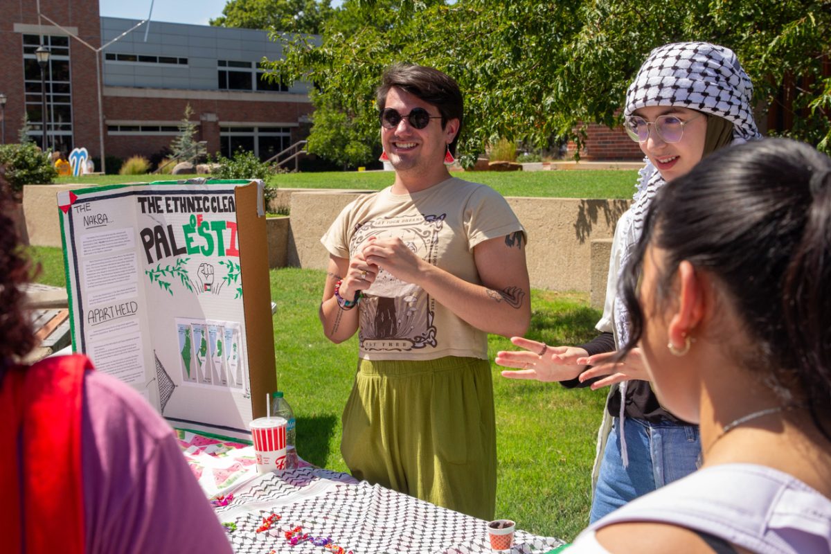 students supporting the palestine movement tell visitors about their efforts and sign scavenger hunt cards. the students are very engaged and interested in participating.