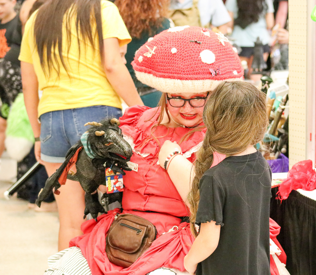 Mary, a member of the "Flint Hill Fairies," talks to a girl about her dragon. "Flint Hill Fairies" is an entertainment-for-hire service that hosts a variety of costumed theatrical events. 