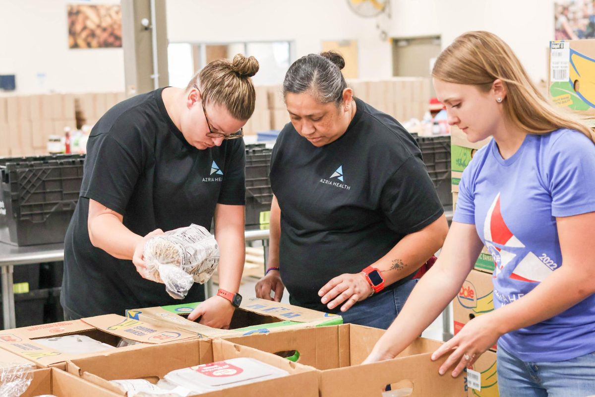 Azria Health staff help sort out bread into the baked good bins. The majority of the volunteers present at Food Bank Friday were staff from Azria Health.