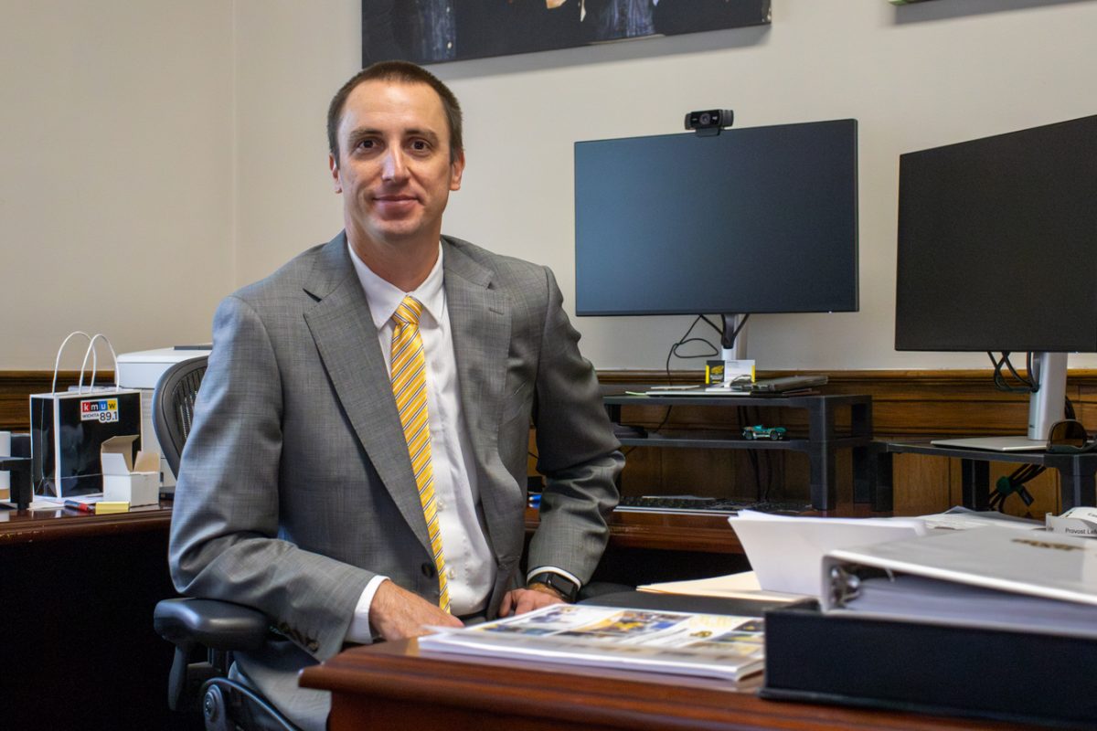 Aaron Mitchell, the new senior vice president for administration, finance and operations, smiles for a photo in his office in Morrison Hall. Mitchell previously served as associate vice president for financial services at Montana State University.