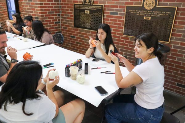 A group of WSU students laugh as they decorate pumpkins and socialize at the Make & Take Pumpkin Painting event hosted by the Student Activities Council.