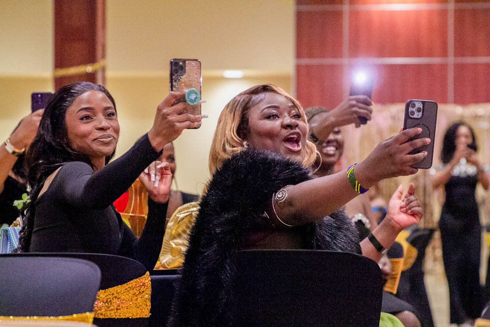 Attendees of Afro Karibbean Night cheer and record videos as students strut down the center of Beggs Ballroom during the event's fashion show. More than a dozen models showcased traditional African and Caribbean wear, as well as designs by Afro-centric designer Kapinga Victoria Tshianyi.