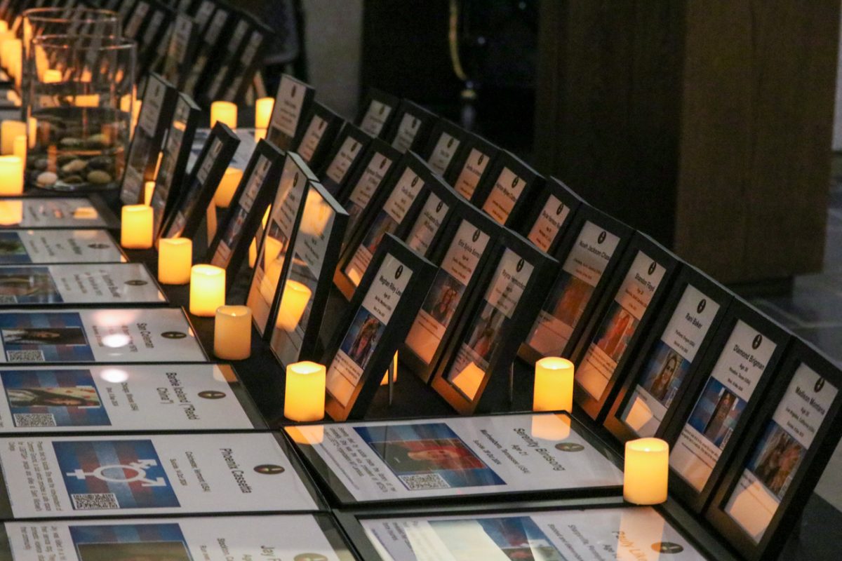 Photos of deceased transgender individuals on a table at the Trans Day of Remembrance vigil. Each photo listed the individuals age and cause of death.