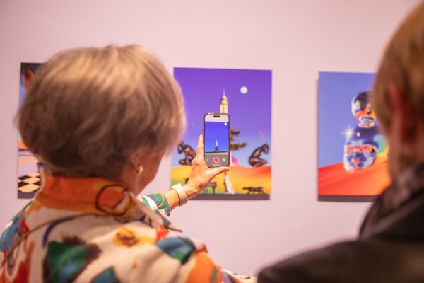 Attendees look at multidisciplinary artist, David Alabo's visual art through a phone camera. The art turned into a video through the screen.