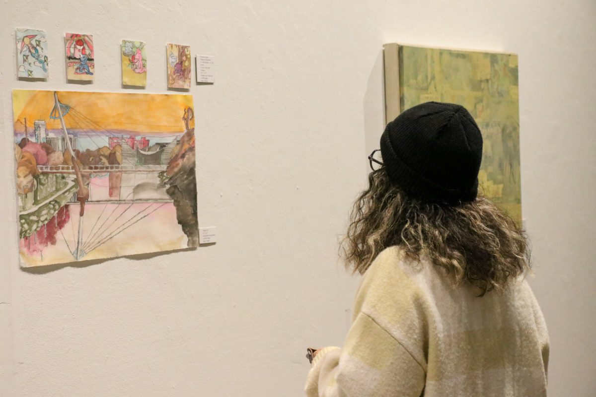 A spectator observes an art piece at the reception of "At Crit's End."