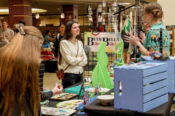 Passersby look over the goods from the Beth and Bella Art booth at the Makers Market on Nov. 12.