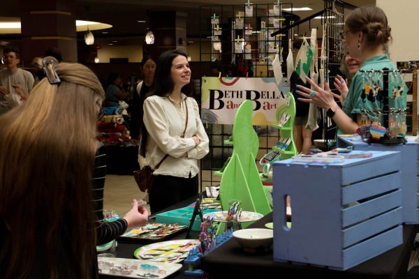 Passersby look over the goods from the Beth and Bella Art booth at the Makers Market on Nov. 12.