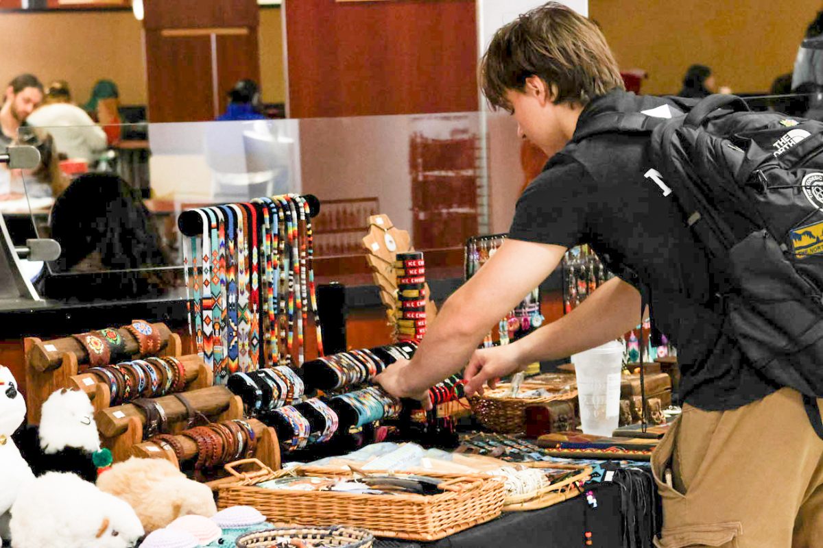 Maverick Lane, a sophomore majoring in graphic design, chooses at bracelet from a booth at the Makers Market.