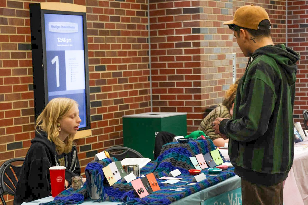 Alec Clavier, a collaborative design major and vendor at the Makers Market, talks with fellow "maker" Sophia Yates at her booth.