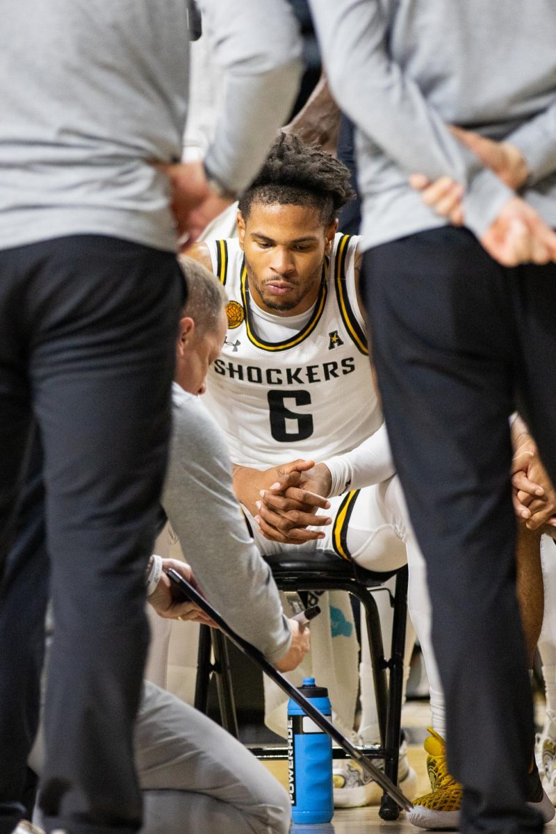 Junior forward Corey Washington listens to head coach Paul Mills during a timeout on Dec. 17. Washington occupied the court for nearly 30 minutes, scoring eight points.