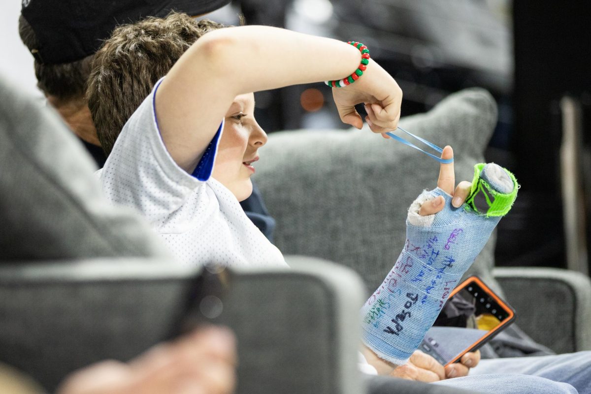 A child sitting on the sideline plays with a rubber band between action at the Wichita State men's basketball game on Dec. 17.