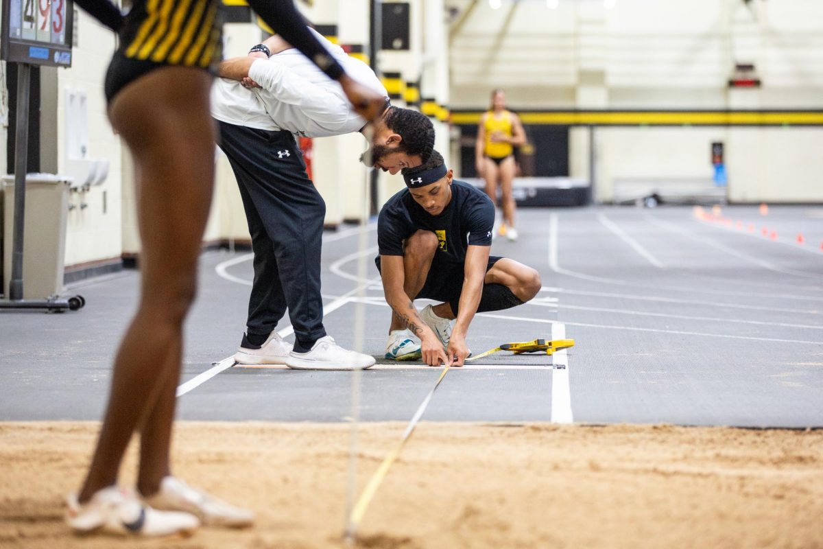 Track and field players and staff mark the point a player reached in the high jump event.