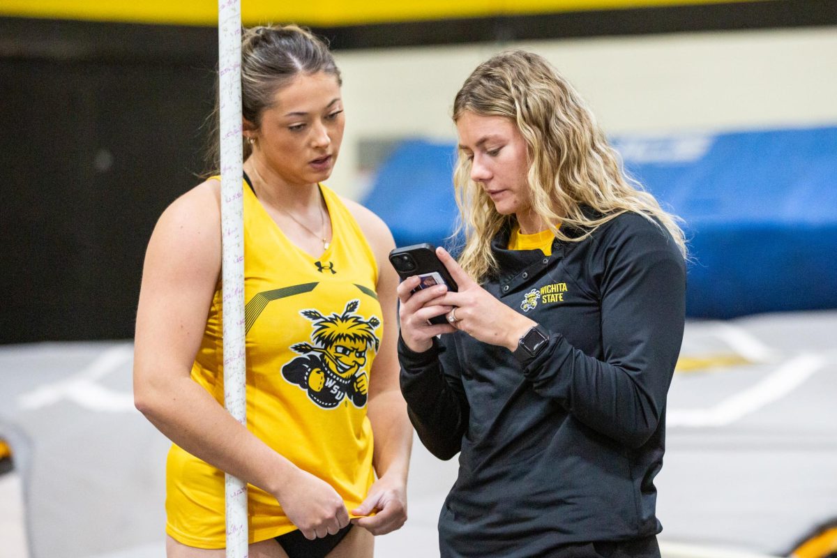 Bailey Hartley watches video of her pole vault performance, recorded by Aliyah Fertig, the pole vault coach for track and field.