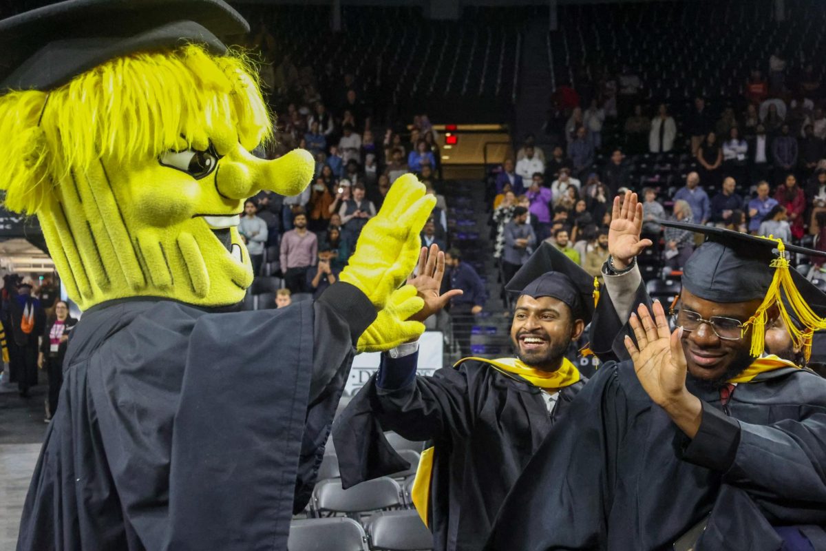 Wushock high-fives graduates as he walks off.