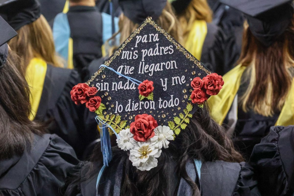 A Wichita State graduate wears her decorated cap. In English, the cap says, "For my parents who came with nothing and gave me everything."