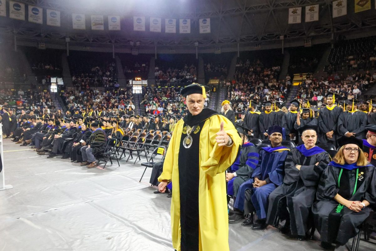 Wichita State President Rick Muma waves on graduates to move forward.