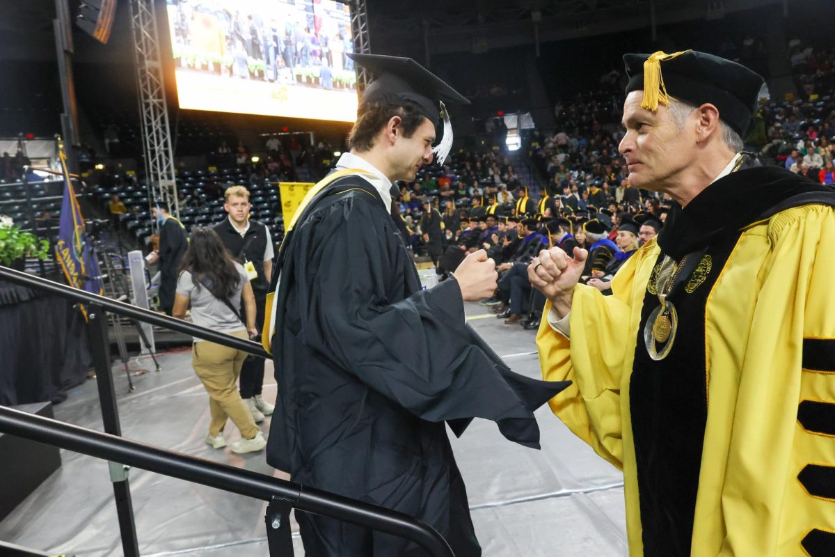 Wichita State President Rick Muma fist bumps Garret Heath. Heath received a Masters of Education.